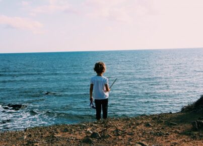 wide-shot-little-child-standing-seashore-near-water